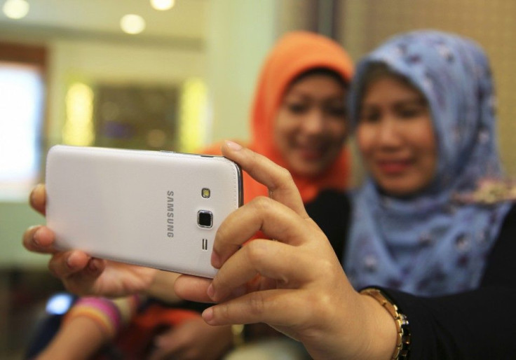 Muslim women take pictures of themselves with a Samsung Galaxy Grand smartphone