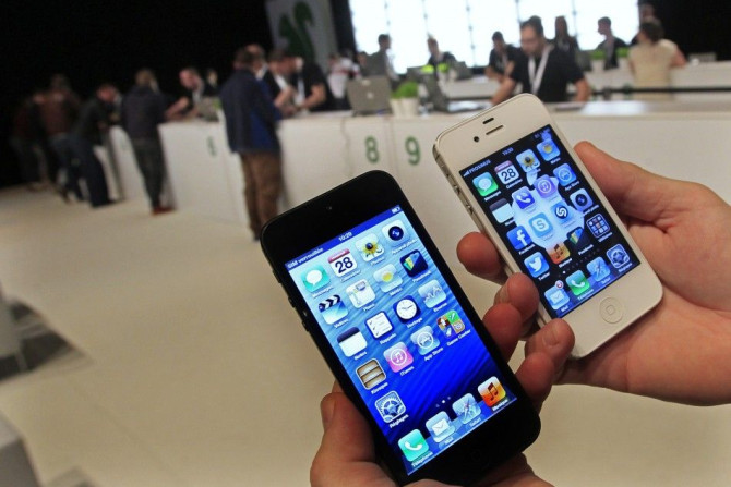 A customer holds up an Apple iPhone 5 (L) and iPhone 4s (R)