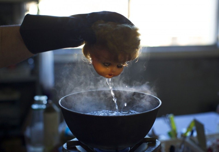 Australian doll repairer Kerry Stuart, a 25-year veteran at Sydney's Doll Hospital, pulls the plastic head of a customers doll out of a bowl of hot water to soften the material before removing and replacing its old eyes