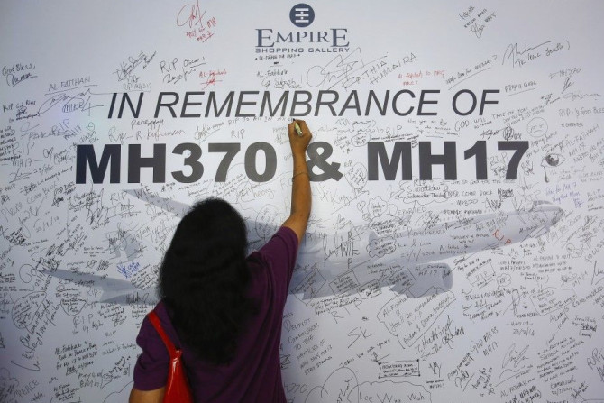 A Woman Writes A Message On A Dedication Board For The Victims Of The Downed Malaysia Airlines Flight MH17 Airliner And The Missing Flight MH370, In Subang Jaya Outside Kuala Lumpur