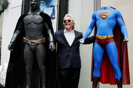 Film Producer Jon Peters Poses With A Batman, Left, And Superman, Right, Costume.