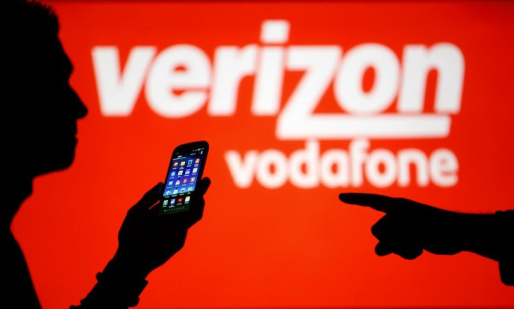A man is silhouetted against a video screen with Vodafone and Verizon texts as he poses with a Samsung Galaxy S3
