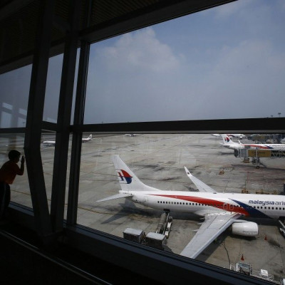 A boy looks at a Malaysia Airlines Boeing 737-800 aircraft (foreground) on the tarmac at Kuala Lumpur International Airport in Sepang outside Kuala Lumpur June 27, 2014. The passengers and crew of the missing Malaysia Airlines Flight MH370 most likely die
