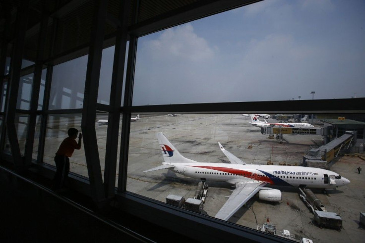 A boy looks at a Malaysia Airlines Boeing 737-800 aircraft (foreground) on the tarmac at Kuala Lumpur International Airport in Sepang outside Kuala Lumpur June 27, 2014. The passengers and crew of the missing Malaysia Airlines Flight MH370 most likely die