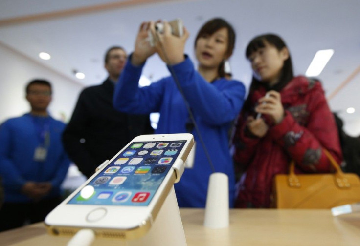 A staff of a China Mobile shop explains a function of the iPhone 5s