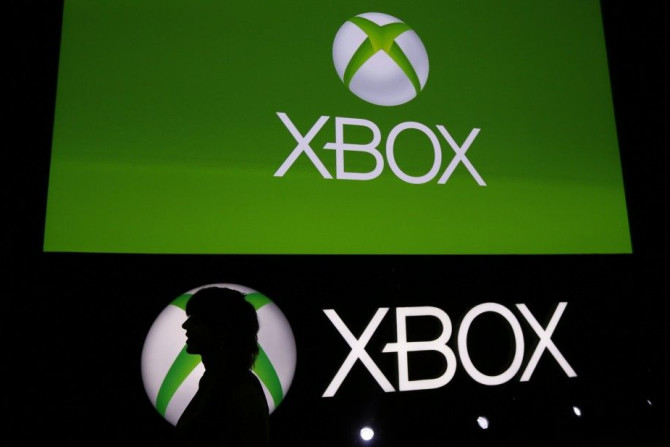 A Spanish Games blogger is silhouetted against the logo of Microsoft's Xbox during the Xbox Play Day 2014, before the Gamescom 2014 fair in Cologne August 12, 2014.