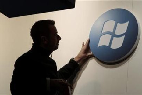 A Worker Adjusts A Logo On The Microsoft Stand