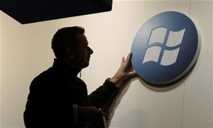 A Worker Adjusts A Logo On The Microsoft Stand