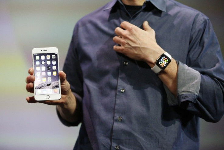 Apple CEO Tim Cook wears the Apple Watch and shows the iPhone 6 Plus during an Apple event at the Flint Center in Cupertino