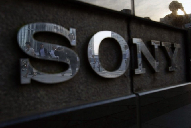 Pedestrians are reflected in a logo of Sony Corp