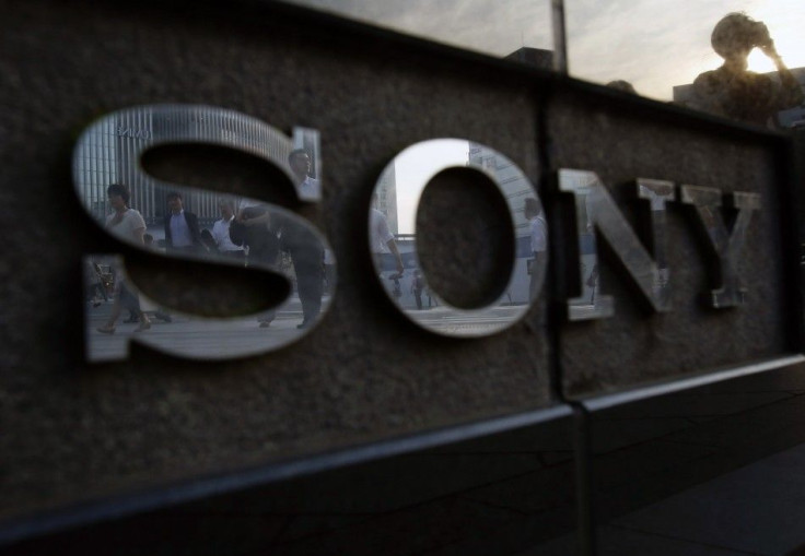 Pedestrians are reflected in a logo of Sony Corp