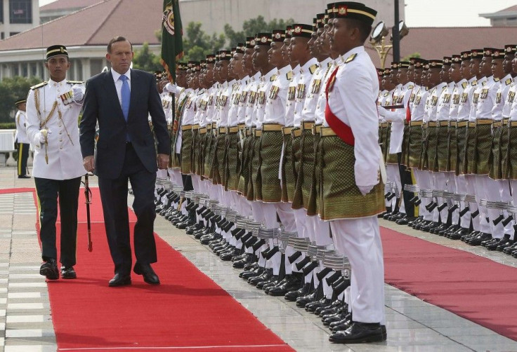 Australian Prime Minister Tony Abbott inspects the guard of honour during an official visit in Putrajaya