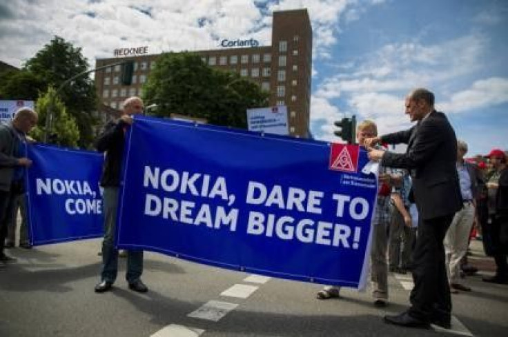 Nokia employees unfold banners during protest denouncing plans to cut jobs at Nokia's Berlin branch in Berlin