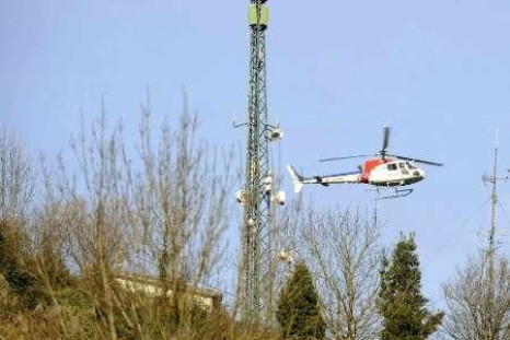 A Basque police helicopter hovers near a television and mobile phone antenna