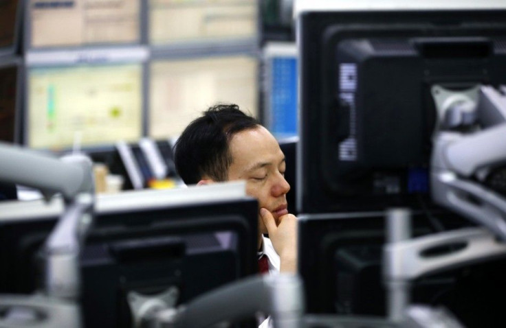 A currency dealer sleeps in front of screens as he works at a dealing room of a bank in Seoul February 6, 2014.