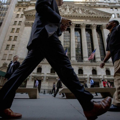 Morning commuters pass by the New York Stock Exchange September 15, 2014.