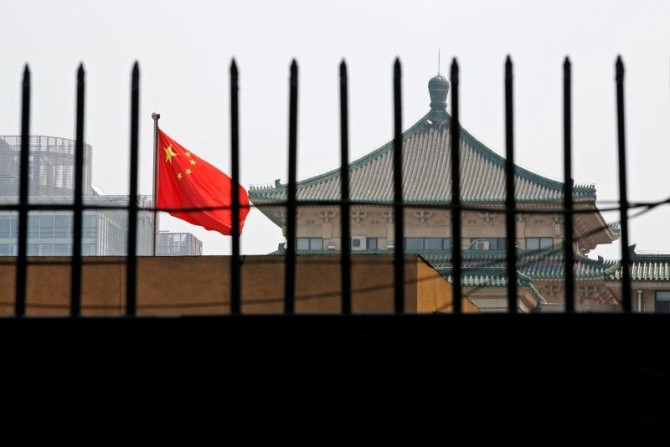 The national flag of China flutters behind a fence of the headquarters of the National Development and Reform Commission (NDRC) in Beijing, in this July 12, 2013