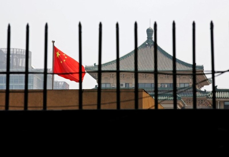 The national flag of China flutters behind a fence of the headquarters of the National Development and Reform Commission (NDRC) in Beijing, in this July 12, 2013