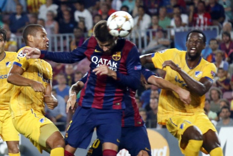 Barcelona's Gerard Pique (C) heads the ball to score a goal against Apoel Nicosia's player Joao Guilherme (L) and Vinicius (R) during their Champions league soccer match at Camp Nou stadium in Barcelona September 17, 2014. REUTERS/Albert Gea 