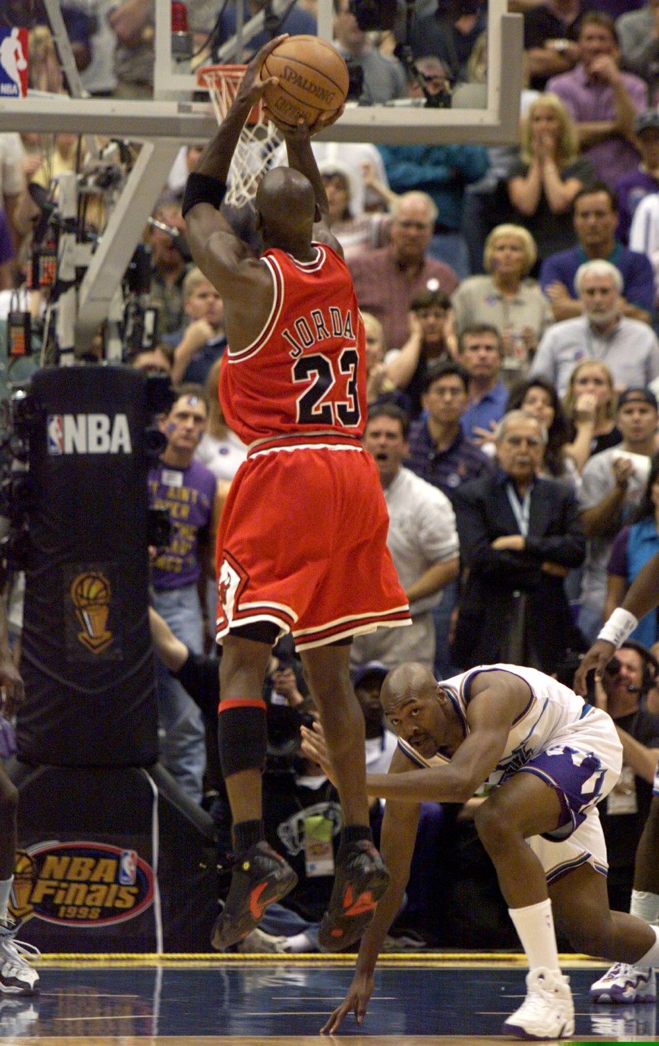 Chicago Bulls Michael Jordan sinks the championship winning basket as Utah Jazz Bryon Russell watches in the final seconds of game six of the NBA finals in Salt Lake City June 14, 1998. Jordans basket gave the Bulls an 87-86 victory and their 6th NBA tit