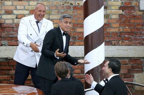 U.S. actor George Clooney  top 2nd L gestures as he leaves by taxi boat to travel to the venue of a gala dinner ahead of his official wedding ceremony in Venice September 27, 2014. 