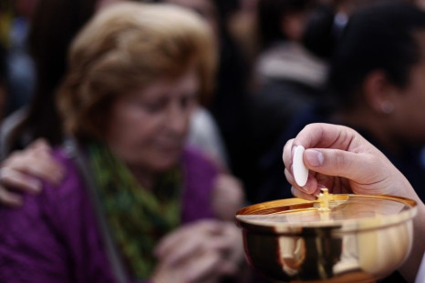A priest holds the communion as Pope Francis leads the canonisation ceremony of Popes John XXIII and John Paul II in St. Peter&#039;s Square at the Vatican April 27, 2014. Pope Francis proclaimed his predecessors John XXIII and John Paul II saints in fron