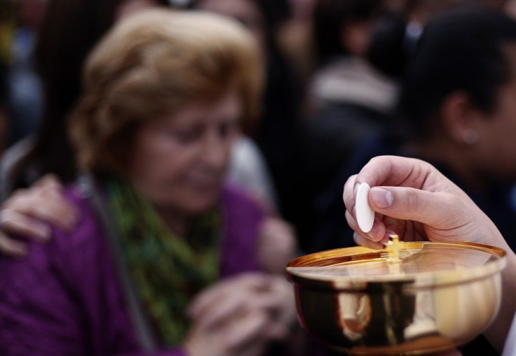 A priest holds the communion as Pope Francis leads the canonisation ceremony of Popes John XXIII and John Paul II in St. Peter&#039;s Square at the Vatican April 27, 2014. Pope Francis proclaimed his predecessors John XXIII and John Paul II saints in fron