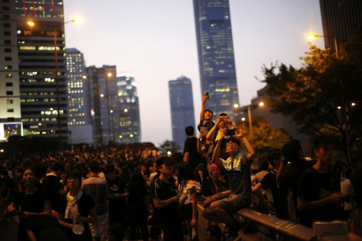 Protesters take pictures with their mobile phones as they block the main street to the financial Central district, outside the government headquarters in Hong Kong 