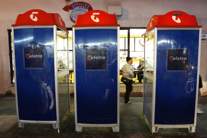 A woman walks past three Telstra public phone booths in suburban Sydney August 9, 2012. Telstra, Australia's biggest phone company, posted a larger-than-expected 5 percent fall in second-half profit as declines in its traditional fixed-line business outwe