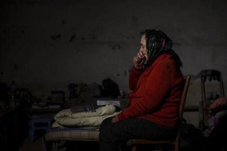 A woman sits inside a basement used as a shelter from the recent shelling
