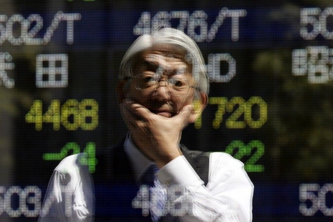 A man is reflected in an electronic stock quotation board outside a brokerage in Tokyo April 11, 2014. Japanese shares tumbled to six-month lows on Friday and could log their worst performance since the March 2011 tsunami and nuclear disaster after a rout