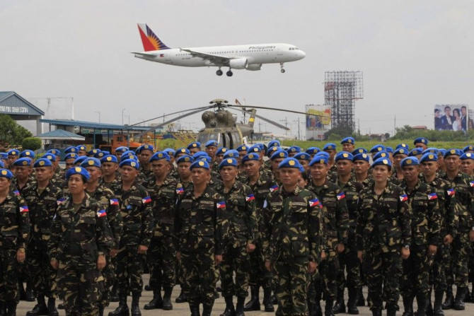 Members of the 157 sailors and marines, of the armed forces of the Philippines contingent joining the United Nations Peacekeeping Force in Haiti, stand at attention an oath during a sending-off ceremony, as a Philippine Airlines plane flies overhead, at t