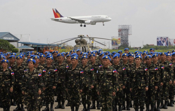 Members of the 157 sailors and marines, of the armed forces of the Philippines contingent joining the United Nations Peacekeeping Force in Haiti, stand at attention an oath during a sending-off ceremony, as a Philippine Airlines plane flies overhead, at t