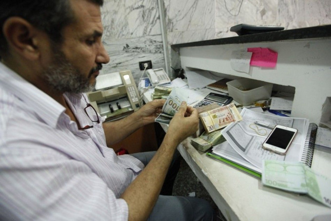 A man counts U.S. dollars at a currency exchange office in central Tripoli, June 3, 2014. Libya's currency is under heavy pressure as a breakdown in security and a collapse of oil revenues due to port blockades have badly disrupted public finances and an 