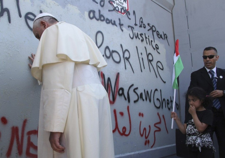 Pope Francis touches the wall that divides Israel from the West Bank, on his way to celebrate a mass in Manger Square next to the Church of the Nativity in the West Bank city of Bethlehem May 25, 2014. Pope Francis made a surprise stop at the hulking wall