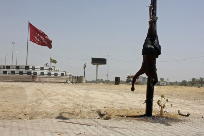 The body of a man is hung upside down in the city of Baquba August 2, 2014. Unidentified gunmen hanged the body of the man who was a member of the Islamic State, formerly known as the Islamic State in Iraq and the Levant (ISIL), according to the local pol