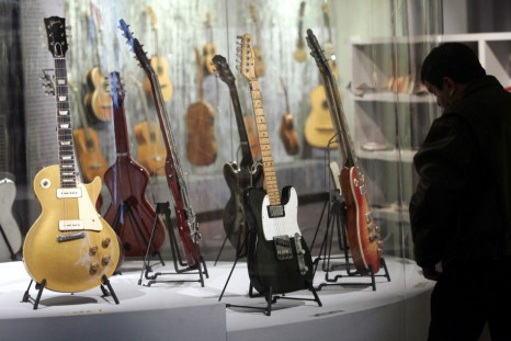 A man admires a 1963 Fender Telecaster Custom guitar belonging to John Lennon (C) and a 1955 Gibson Les Paul Goldtop guitar belonging to David Gilmour of Pink Floyd (L) at the &#039;Travelling Guitars&#039; exhibition at the Cite de la Musique in Paris Oc