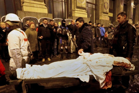 A man holds the hand of his dead son during the transfer of over a dozen of corpses from a hotel lobby to a local hospital following clashes with riot police at Independence Square in Kiev February 20, 2014.