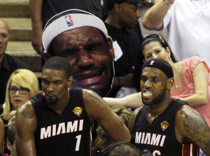 Miami Heat&#039;s Chris Bosh (L) and LeBron James wait to enter the game after a timeout as a San Antonio Spurs&#039; fan mocks James during the third quarter in Game 5 of their NBA Finals basketball series in San Antonio, Texas, June 15, 2014
