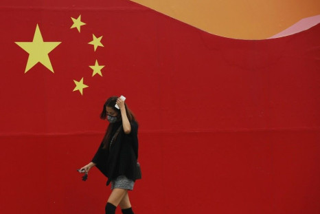 A woman wearing a mask walks past a wall painted with China's national flag in central Beijing, October 9, 2014. Beijing issued a yellow alert for air pollution on Wednesday with smog forecast to continue for the next three days until Saturday, said the B