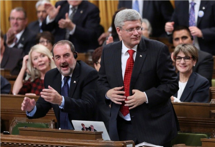 Canada's Prime Minister Stephen Harper (R) stands to vote in favour of a government motion to participate in U.S.-led air strikes against Islamic State