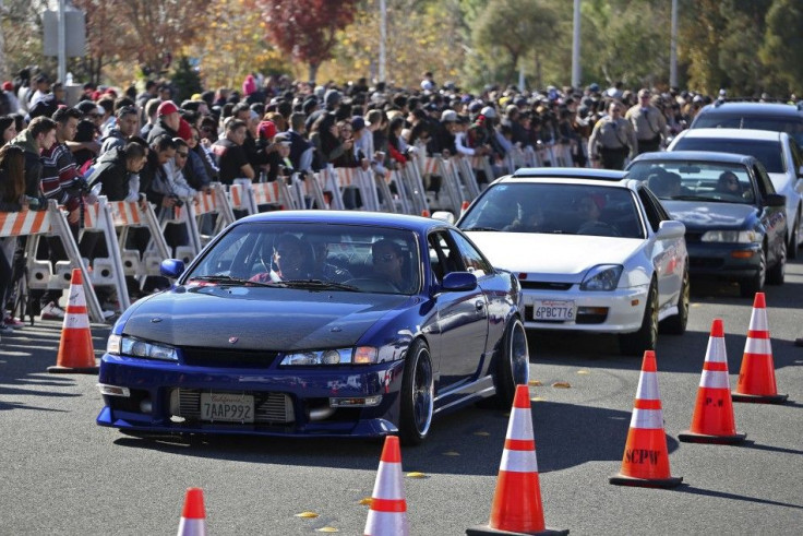 Vehicles are driven past a crowd attending an unofficial memorial event for "Fast & Furious" star Paul Walker