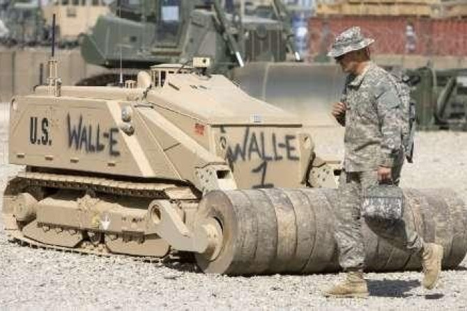 A U.S. Army's soldier walks past a de-mining robot