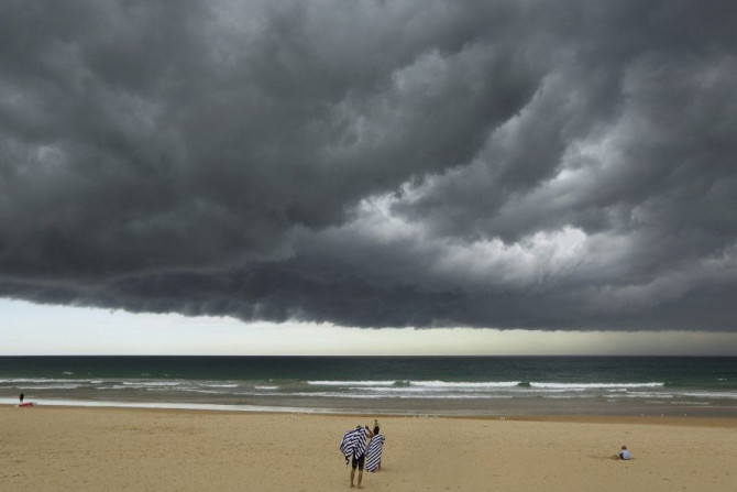 A storm cloud passes over bathers who prepare to leave Sydney&#039;s Manly Beach