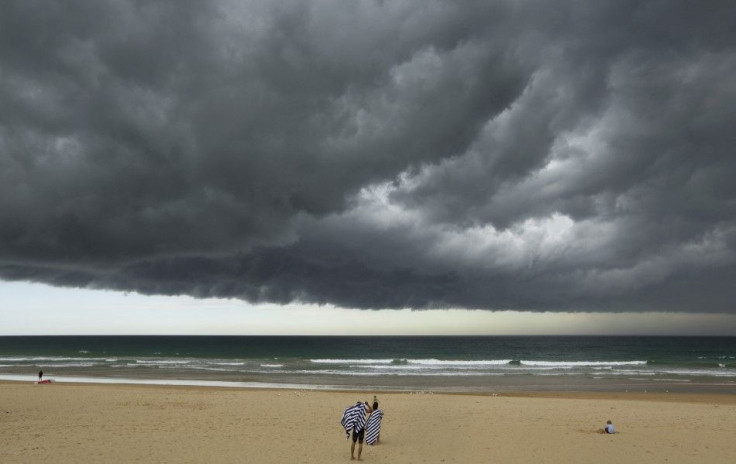 A storm cloud passes over bathers who prepare to leave Sydney&#039;s Manly Beach