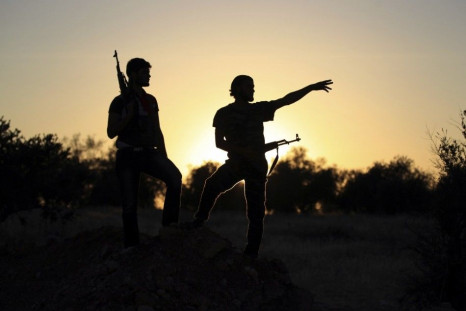 Free Syrian Army fighters are silhouetted as they stand on one of the front lines of Wadi Al-Daif camp in the southern Idlib countryside September 18, 2014. Picture taken September 18, 2014. REUTERS/Khalil Ashawi
