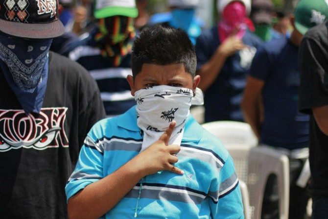 A young member of the Mara MS 13 street gang gestures while singing the national anthem during an event sponsored by the country's Catholic church at a park in San Vicente April 5, 2013. Members of the country's two most powerful gangs MS-13 and 18th Stre