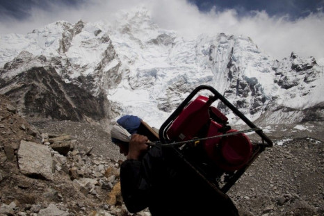 A porter carries a generator towards Everest Base Camp from Gorak Shep with the Himalayan mountain range seen in the background, May 03, 2011. Porters walk for weeks, sometimes carrying supplies heavier than their own body weight. They do not sit down whe
