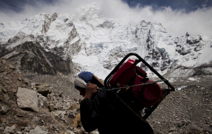 A porter carries a generator towards Everest Base Camp from Gorak Shep with the Himalayan mountain range seen in the background, May 03, 2011. Porters walk for weeks, sometimes carrying supplies heavier than their own body weight. They do not sit down whe