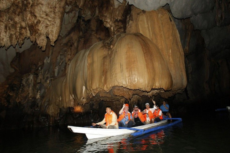 Puerto Princesa Mayor Edward Hagedorn (C) sits with New Seven Wonders Foundation President Bernard Weber (3rd R) and Director Jean-Paul de la Fuente (2nd L) on a banca as it passes under a mushroom-shaped rock formation inside the Puerto Princesa Subterra